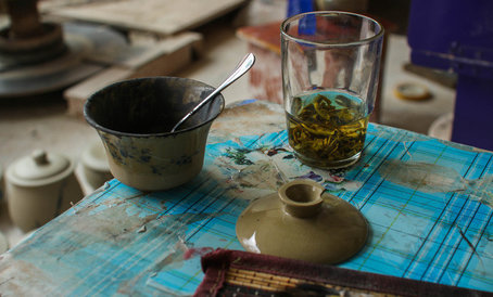 Тушь для росписи налита в гайвань, а зеленый чай заварен в стакане, художник за работой.